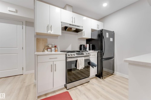Kitchen featuring light-toned flooring, white cabinetry with silver hardware, a stainless steel range, and a black refrigerator - 1663 Cavanagh Boulevard Sw, Edmonton, AB - Indoor Photo Showing Kitchen
