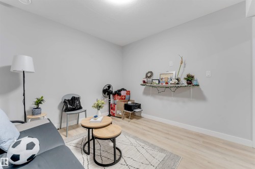 This room features light-colored walls, light wood flooring, and a decorative wall shelf - 1663 Cavanagh Boulevard Sw, Edmonton, AB - Indoor Photo Showing Other Room