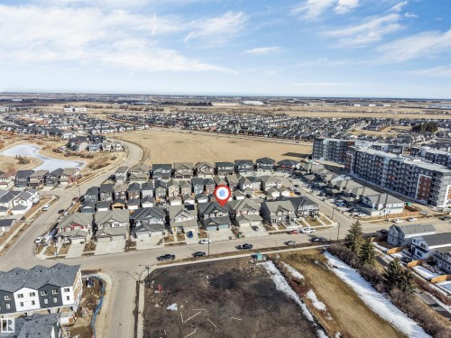 Aerial view of the property and surrounding neighborhood, featuring residential homes, apartment buildings, and a pond - 1663 Cavanagh Boulevard Sw, Edmonton, AB - Outdoor With View