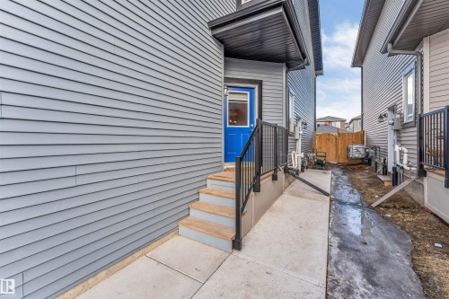 The property features a bold blue entry door with a covered porch - 1663 Cavanagh Boulevard Sw, Edmonton, AB - Outdoor With Exterior