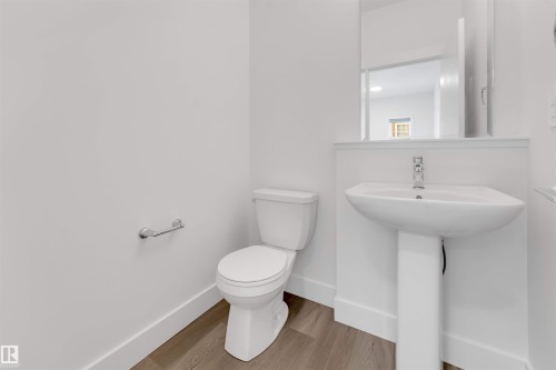 A clean, modern bathroom with a white pedestal sink, toilet, and light wood-style flooring - 1663 Cavanagh Boulevard Sw, Edmonton, AB - Indoor Photo Showing Bathroom