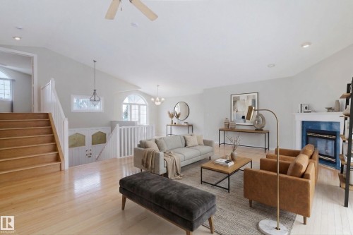 The living area features hardwood floors, vaulted ceilings, and a fireplace with a blue surround - 1641 Forbes Way, Edmonton, AB - Indoor Photo Showing Living Room With Fireplace
