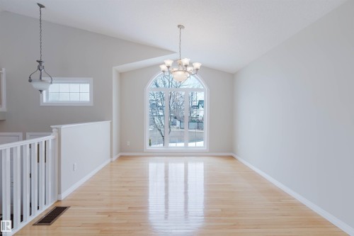 This spacious room features vaulted ceilings, hardwood flooring, and a large arched window - 1641 Forbes Way, Edmonton, AB - Indoor Photo Showing Other Room
