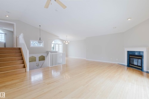 Spacious living area featuring hardwood floors, a fireplace with a blue-tiled surround, and a ceiling fan - 1641 Forbes Way, Edmonton, AB - Indoor With Fireplace