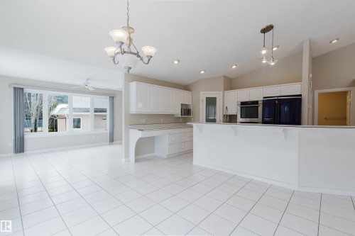 Spacious open-concept living area featuring white tile flooring, white cabinetry, and large windows providing ample natural light - 1641 Forbes Way, Edmonton, AB - Indoor Photo Showing Kitchen