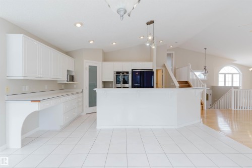 Open concept kitchen featuring white cabinetry, an island, and white tile flooring - 1641 Forbes Way, Edmonton, AB - Indoor Photo Showing Kitchen