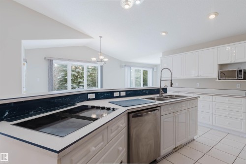 The kitchen features white cabinetry, a built-in cooktop, and a stainless steel dishwasher - 1641 Forbes Way, Edmonton, AB - Indoor Photo Showing Kitchen With Double Sink