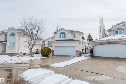 The property features a two-car garage, a paved driveway, and a light-colored exterior finish - 1641 Forbes Way, Edmonton, AB - Outdoor With Facade