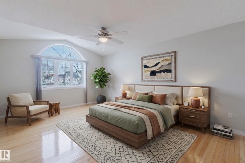 This bright room features hardwood flooring, a vaulted ceiling with a fan, and a large arched window - 1641 Forbes Way, Edmonton, AB - Indoor Photo Showing Bedroom