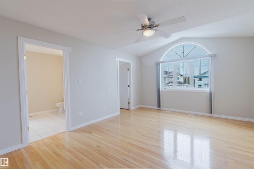 This spacious room features light hardwood floors, a vaulted ceiling, and a ceiling fan with integrated lighting - 1641 Forbes Way, Edmonton, AB - Indoor Photo Showing Other Room