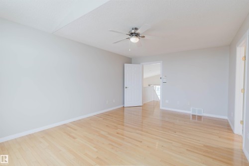 This room features light hardwood flooring, a ceiling fan with integrated lighting, and neutral-toned walls - 1641 Forbes Way, Edmonton, AB - Indoor Photo Showing Other Room