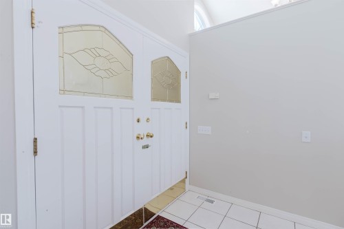 Entryway featuring a white double door with decorative glass inserts, polished brass hardware, and white tile flooring - 1641 Forbes Way, Edmonton, AB - Indoor Photo Showing Other Room