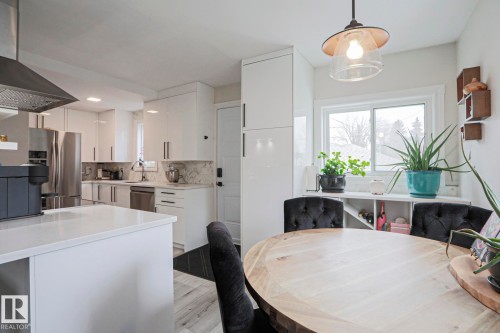 The property features a bright kitchen with white cabinetry and stainless steel appliances, including a range hood, refrigerator, and dishwasher - 9319 92 Street, Edmonton, AB - Indoor