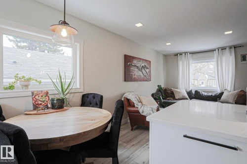 The dining area features a light-toned wooden table and a clear glass pendant light fixture - 9319 92 Street, Edmonton, AB - Indoor Photo Showing Dining Room