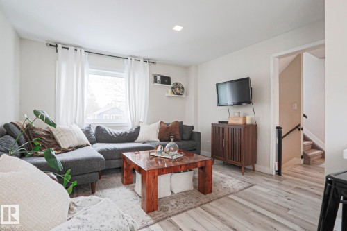 Living area featuring light-toned flooring, recessed lighting, and a window with white curtains - 9319 92 Street, Edmonton, AB - Indoor Photo Showing Living Room