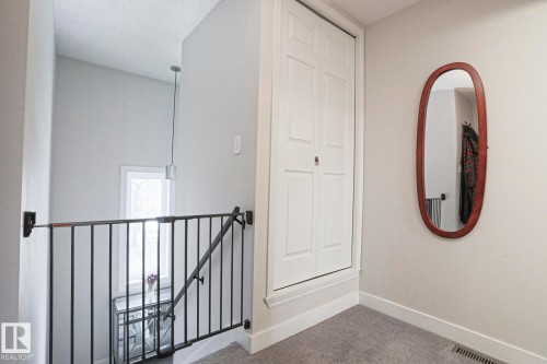 The property features an interior landing with carpeted flooring and light-colored walls - 9319 92 Street, Edmonton, AB - Indoor Photo Showing Other Room