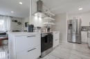 The kitchen features white cabinetry with dark hardware, stainless steel appliances including a refrigerator and range, and light-toned flooring - 9319 92 Street, Edmonton, AB  - Indoor Photo Showing Kitchen With Stainless Steel Kitchen 