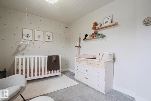 This room features neutral-toned walls, gray carpeting, and a white crib - 9319 92 Street, Edmonton, AB - Indoor