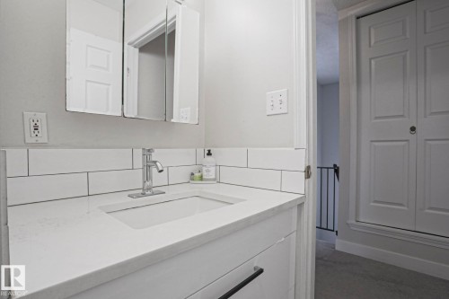 Bathroom vanity with an integrated sink, polished chrome faucet, and subway tile backsplash - 9319 92 Street, Edmonton, AB - Indoor Photo Showing Bathroom