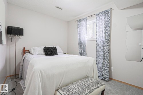 This room features light gray walls, a window with patterned curtains, and gray carpeting - 9319 92 Street, Edmonton, AB - Indoor Photo Showing Bedroom