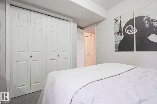 Bedroom featuring neutral colored walls, carpeting, and bi-fold closet doors - 9319 92 Street, Edmonton, AB - Indoor Photo Showing Bedroom