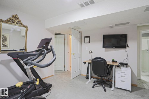 This versatile space offers light gray carpeting and white walls, suitable for a home office or exercise area - 9319 92 Street, Edmonton, AB - Indoor Photo Showing Gym Room