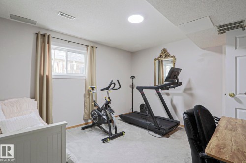 This room features light-colored walls, carpeted floors, and a window with drapes - 9319 92 Street, Edmonton, AB - Indoor Photo Showing Gym Room