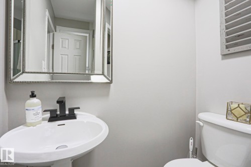This bathroom features a white pedestal sink with a modern black faucet - 9319 92 Street, Edmonton, AB - Indoor Photo Showing Bathroom
