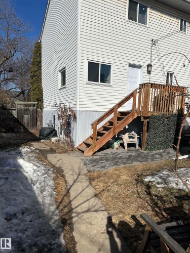 The property features white siding and multiple windows, with a wooden deck and stairs leading to an outdoor patio area - 9319 92 Street, Edmonton, AB - Outdoor With Deck Patio Veranda With Exterior