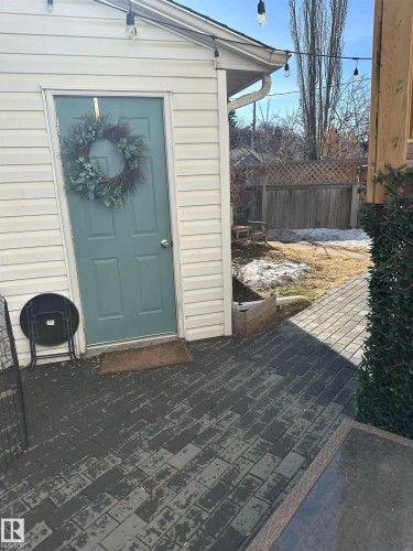 The property features white siding and a light blue door, complemented by string lights overhead - 9319 92 Street, Edmonton, AB - Outdoor With Exterior