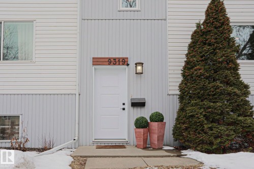 The property features a white paneled exterior, a white front door, and a concrete pathway leading to the entrance - 9319 92 Street, Edmonton, AB - Outdoor With Exterior