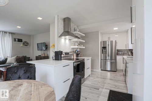 The kitchen features white cabinetry, a white countertop, stainless steel appliances, and a range hood - 9319 92 Street, Edmonton, AB - Indoor Photo Showing Kitchen With Stainless Steel Kitchen