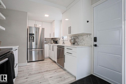 The kitchen features white cabinetry, stainless steel appliances, and light-toned flooring - 9319 92 Street, Edmonton, AB - Indoor Photo Showing Kitchen With Stainless Steel Kitchen