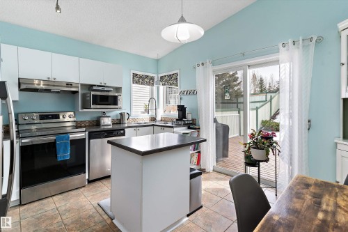 The kitchen features white cabinetry, stainless steel appliances, and a central island - 322 Pearson Crescent, Edmonton, AB - Indoor Photo Showing Kitchen