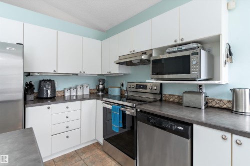 This kitchen features white cabinetry, stainless steel appliances, and a tiled backsplash - 322 Pearson Crescent, Edmonton, AB - Indoor Photo Showing Kitchen