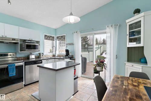 The kitchen features white cabinetry, stainless steel appliances, and a central island - 322 Pearson Crescent, Edmonton, AB - Indoor Photo Showing Kitchen With Double Sink