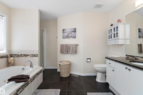 Bathroom featuring a built-in bathtub with tiled surround, a separate shower enclosure, and a vanity with a dark countertop and white cabinetry - 322 Pearson Crescent, Edmonton, AB - Indoor Photo Showing Bathroom