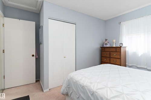 The room features light blue walls, a white bi-fold closet door, and a window with sheer white curtains - 322 Pearson Crescent, Edmonton, AB - Indoor Photo Showing Bedroom