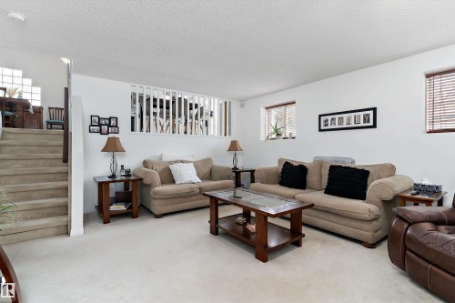 Spacious living area featuring light-colored carpet, white walls, and stairs with carpeted treads - 322 Pearson Crescent, Edmonton, AB - Indoor Photo Showing Living Room