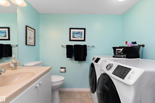 This room features a vanity with an integrated sink, a toilet, a washer, and a dryer - 322 Pearson Crescent, Edmonton, AB - Indoor Photo Showing Laundry Room
