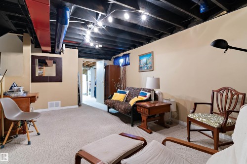 This versatile finished space features a neutral carpet, painted walls, and an exposed ceiling with string lighting, offering an adaptable area for various uses - 322 Pearson Crescent, Edmonton, AB - Indoor Photo Showing Basement