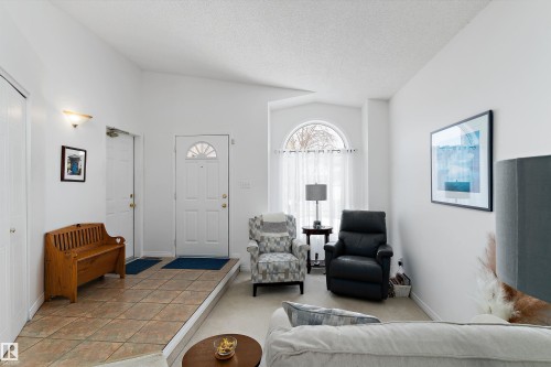 The bright living area features a front entry door with an arched window, an additional arched window with sheer curtains, and a tiled entryway - 322 Pearson Crescent, Edmonton, AB - Indoor