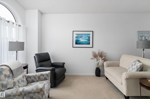This inviting living area features light-colored carpeting, white walls, and a large arched window with sheer white curtains - 322 Pearson Crescent, Edmonton, AB - Indoor Photo Showing Living Room