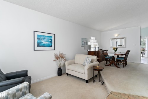 The property features an open living and dining area with light-colored carpeting, white walls, and a textured ceiling - 322 Pearson Crescent, Edmonton, AB - Indoor Photo Showing Living Room