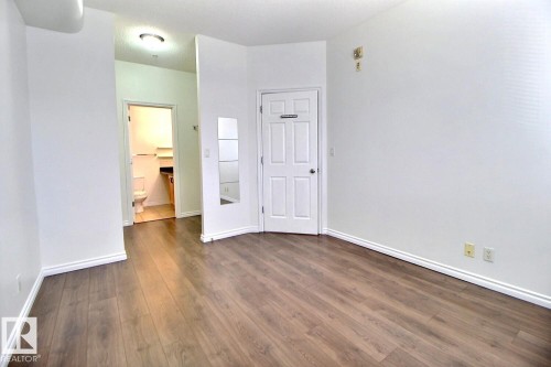This versatile room features durable wood-look flooring and clean white walls, providing a neutral canvas - 209 10235 112 Street, Edmonton, AB - Indoor Photo Showing Other Room