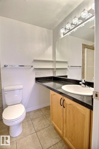 Bathroom featuring a vanity with a light wood finish, a black countertop, and an integrated sink - 209 10235 112 Street, Edmonton, AB - Indoor Photo Showing Bathroom