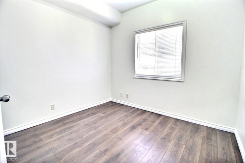 This room features durable plank flooring, white walls, and a window with blinds - 209 10235 112 Street, Edmonton, AB - Indoor Photo Showing Other Room