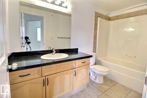 Bathroom featuring a light wood vanity with a dark countertop and an integrated sink - 209 10235 112 Street, Edmonton, AB - Indoor Photo Showing Bathroom