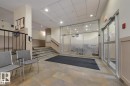 This space features tile flooring, paneling on the walls, and a staircase with a black handrail - 209 10235 112 Street, Edmonton, AB  - Indoor Photo Showing Other Room 