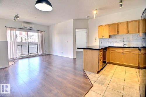 Open concept living space featuring hardwood floors in the main area and tile flooring in the kitchen - 209 10235 112 Street, Edmonton, AB - Indoor Photo Showing Kitchen With Double Sink